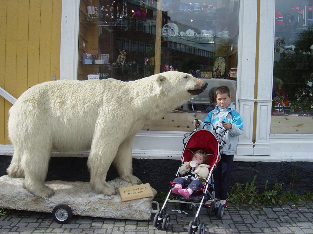 Barn poserer ved en utstoppet isbjørn i Tromsø.