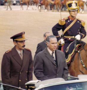 Fotografi av Jorge Videla, Argentinas president 1976-81, mens han står oppreist i en bilkortesje i 1976.